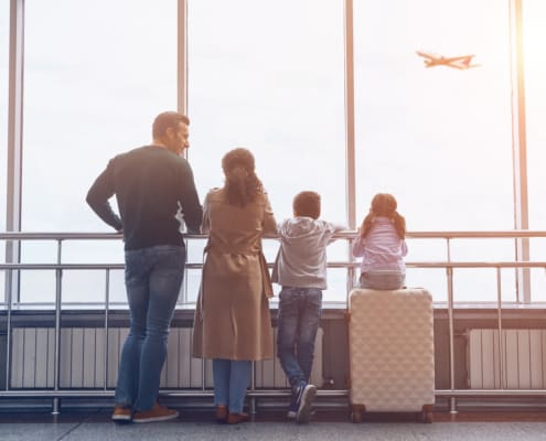 Full Length Of Family With Two Little Kids Looking At The Flying Airplane