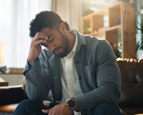 Home, Headache And Man On Sofa, Stress And Tired With Pain, Burnout And Frustrated In Living Room. Apartment, Mental Health Or Person On Couch, Migraine And Exhausted With Anxiety, Worry Or Brain Fog