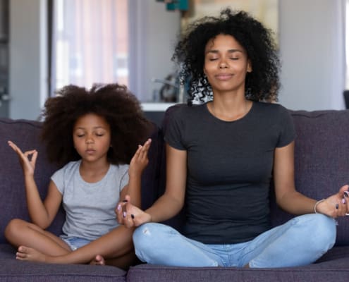 Mindful African Mom With Funny Kid Daughter Doing Yoga Together