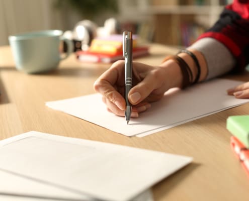 Student Hand Writing Letter At Home In The Night